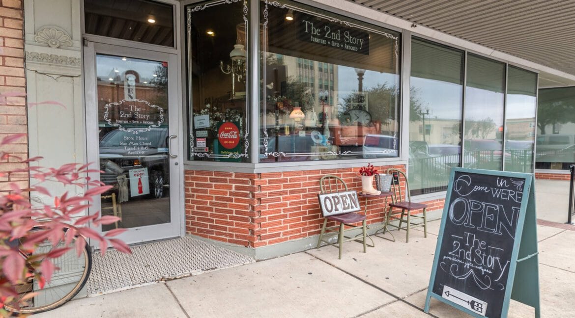 Exterior view of The 2nd Story shop in Bryan, Texas with open sign and sidewalk seating.