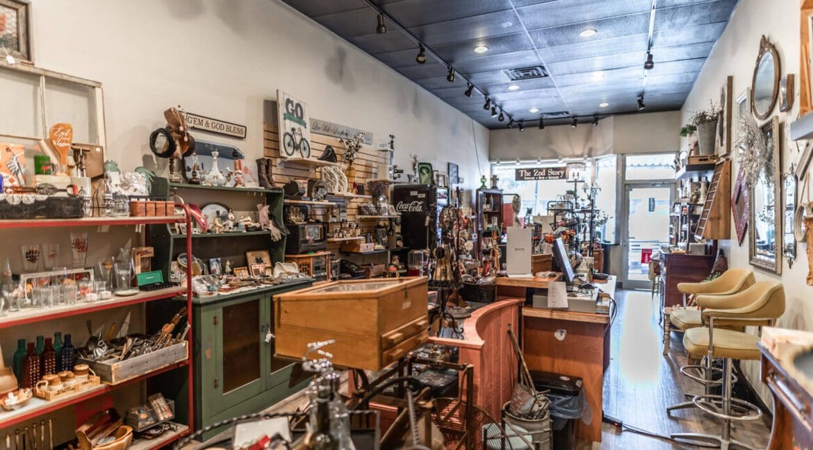 Interior of a retail store with various vintage and antique items on shelves and tables.