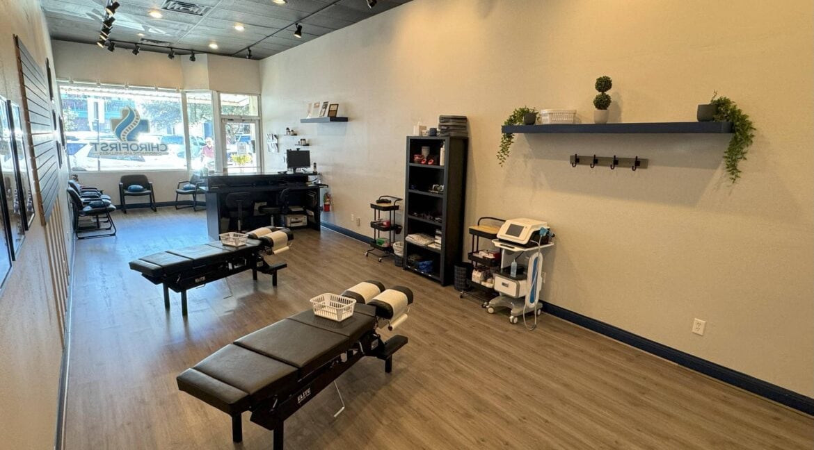 Empty massage therapy room with two massage tables and shelves on the wall.