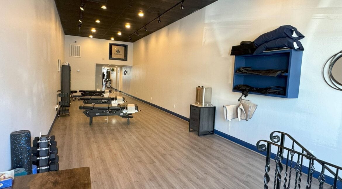 Empty fitness studio with workout equipment and mirrors on the wall.